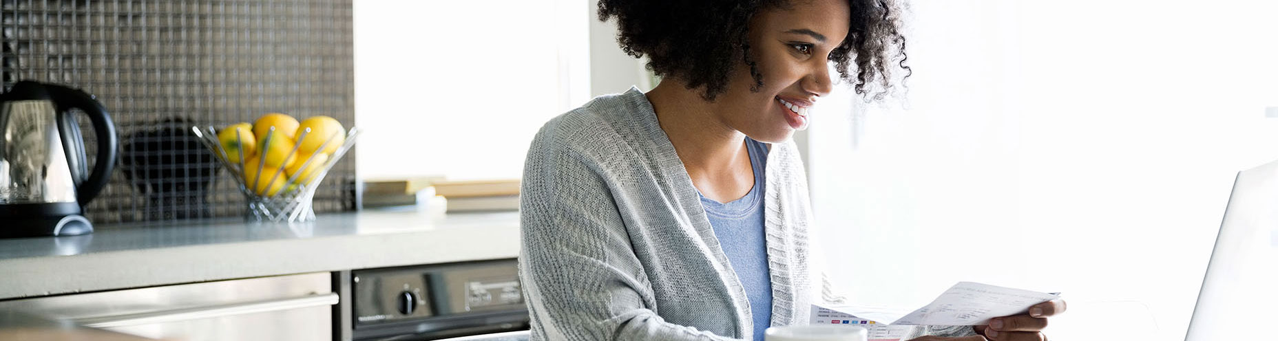 woman smiling with bill looking down at laptop