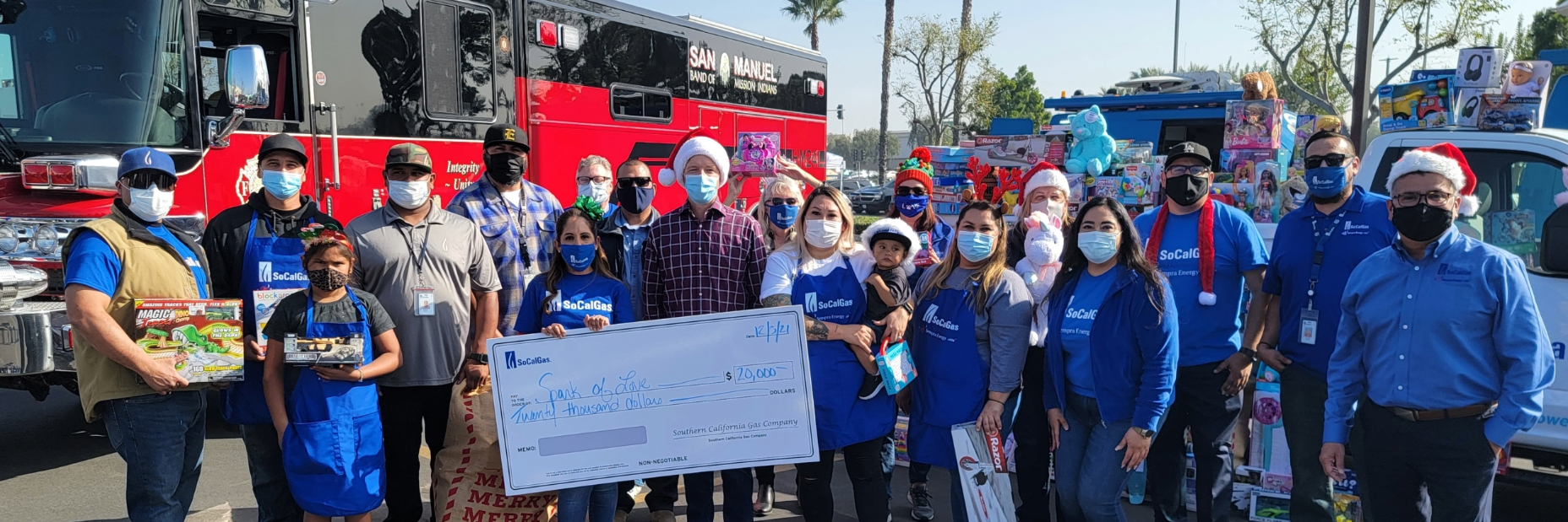 SoCalGas volunteers holding a giant check and toys posing for a photo