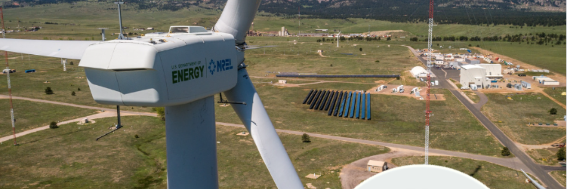 Image of a windmill at the propellers with solar panels in the distance on the ground below
