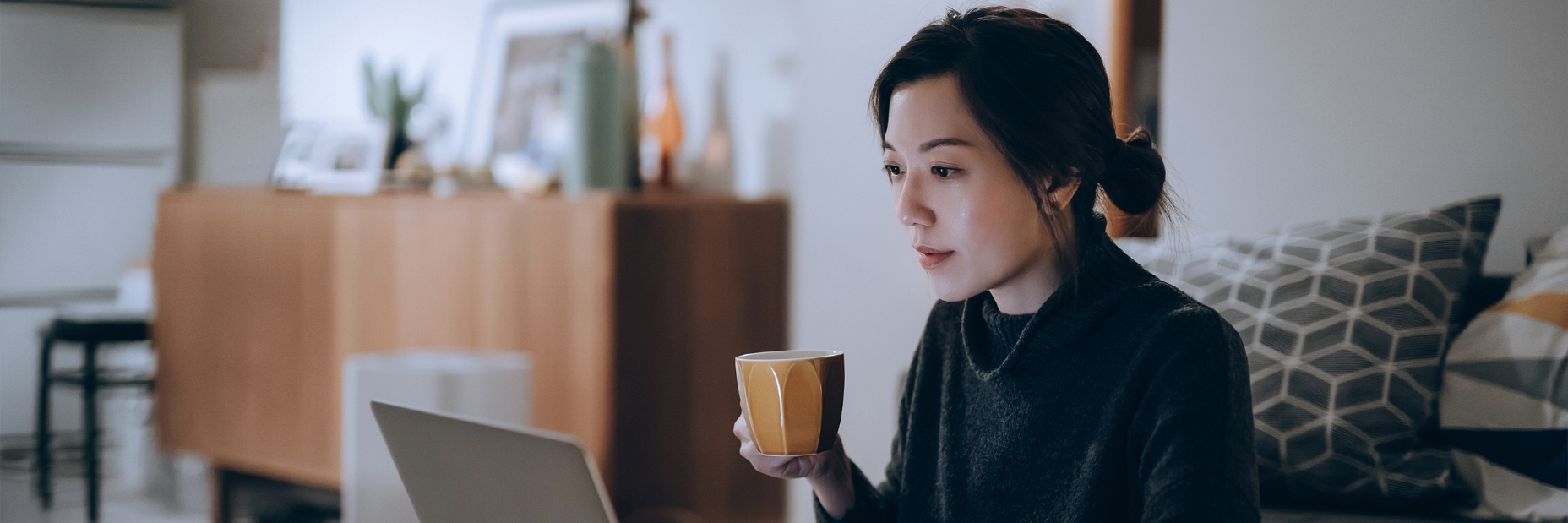 Lady drinking coffee and looking at her computer