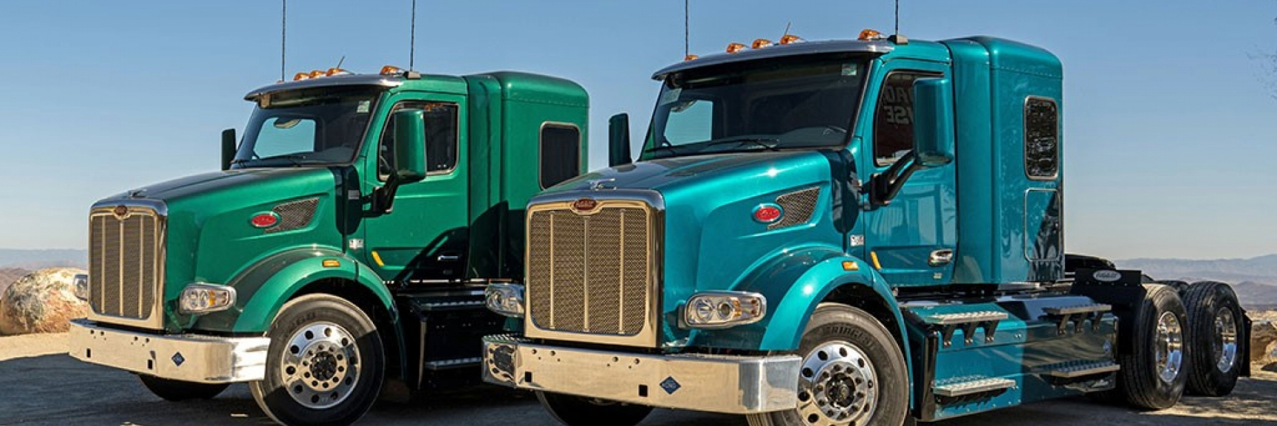 Heavy Duty Trucks sitting on the side of an oulook with a valley in the background