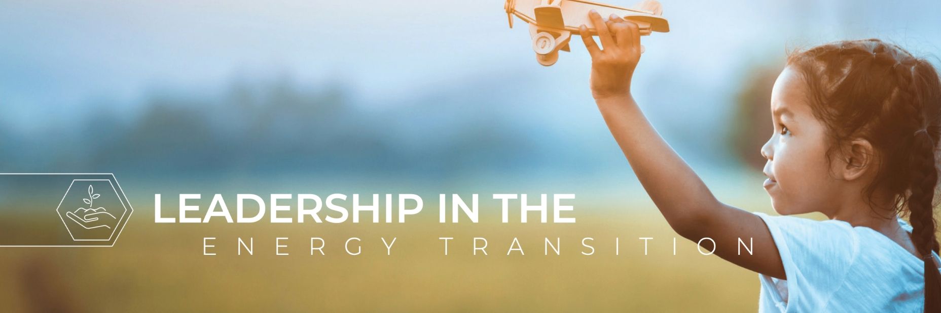 Little girl playing with wooden handheld plane with the text "leadership in the energy transition" in the foreground