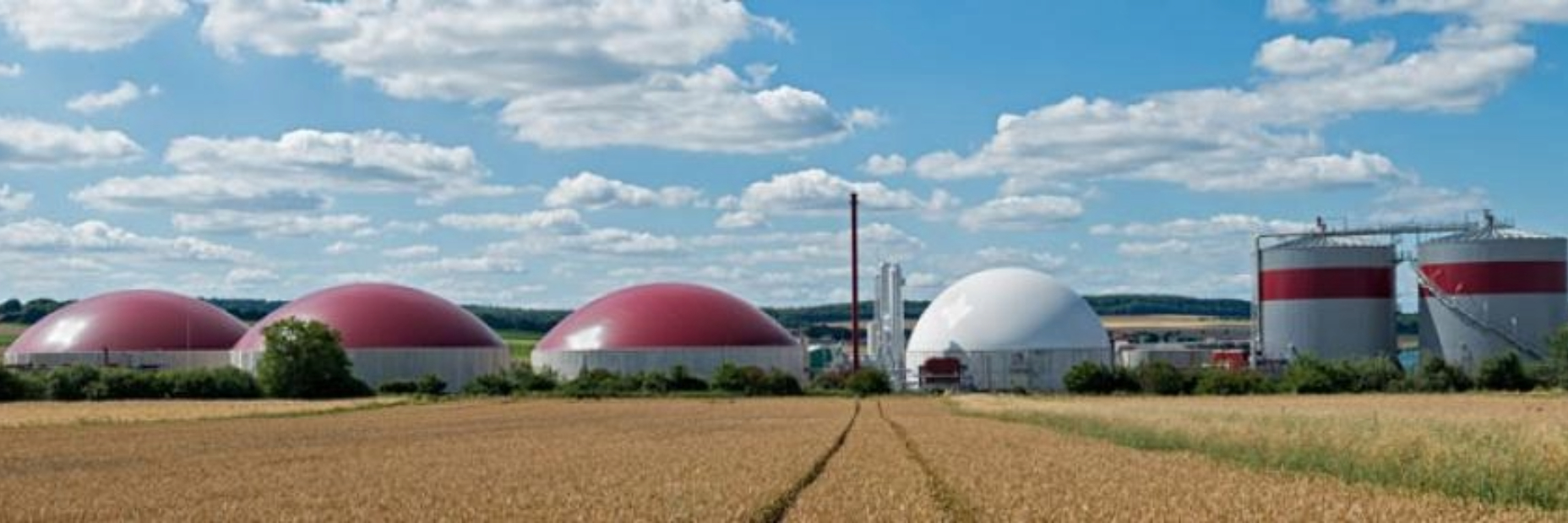 Renewable natural gas facility where waste is being turned into fuel with fields and a mostly sunny skie in the background